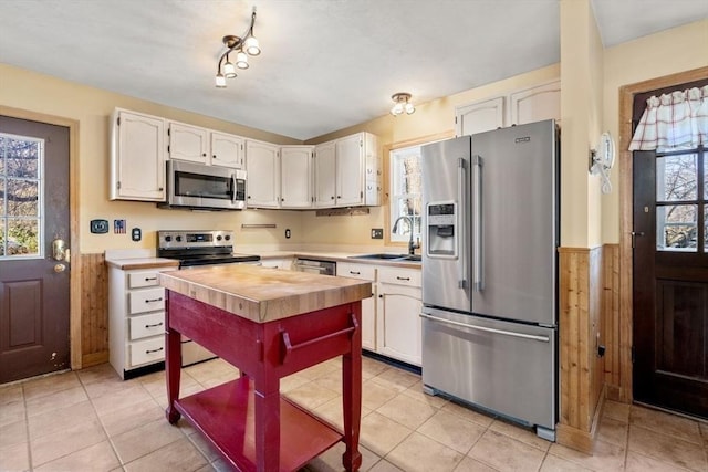 kitchen with sink, light tile patterned floors, white cabinets, and appliances with stainless steel finishes