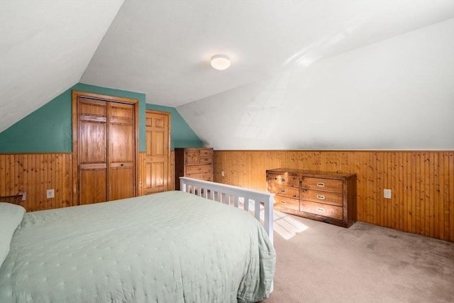 bedroom featuring light colored carpet, lofted ceiling, a closet, and wood walls