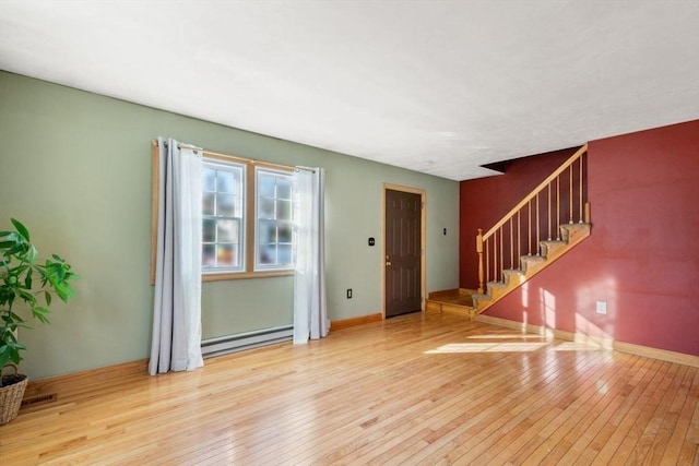 empty room featuring a baseboard radiator and light hardwood / wood-style flooring