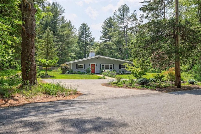 128 Clinton St, Hopkinton, MA 01748 - view of front of house with driveway, a front lawn, a chimney, and a wooded view