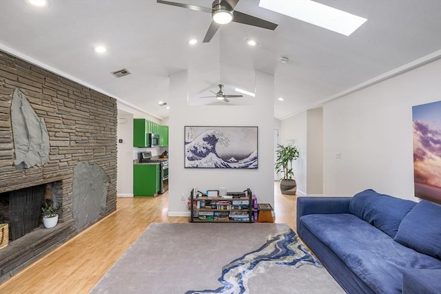128 Clinton St, Hopkinton, MA 01748 - living area featuring a ceiling fan, light wood-type flooring, a fireplace, lofted ceiling, and a skylight