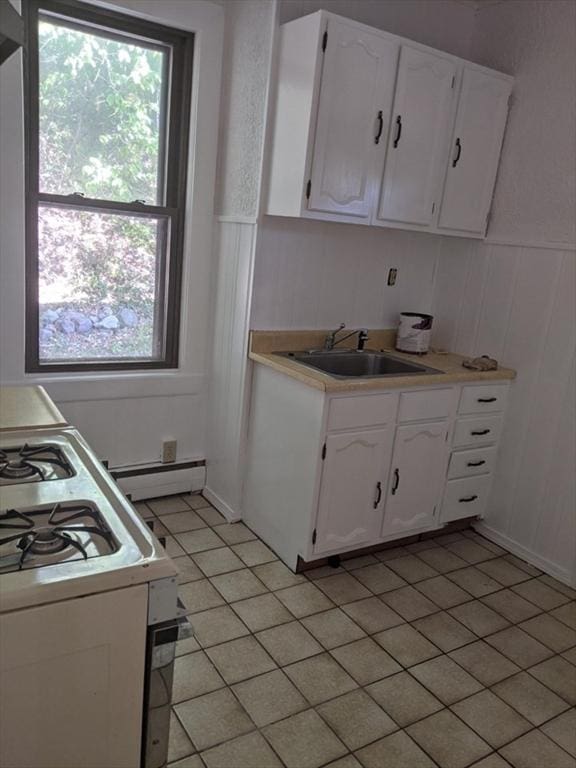 kitchen featuring white gas stove, sink, white cabinets, and a baseboard heating unit