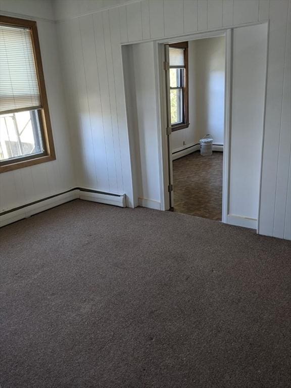 unfurnished room featuring plenty of natural light, carpet floors, and a baseboard heating unit