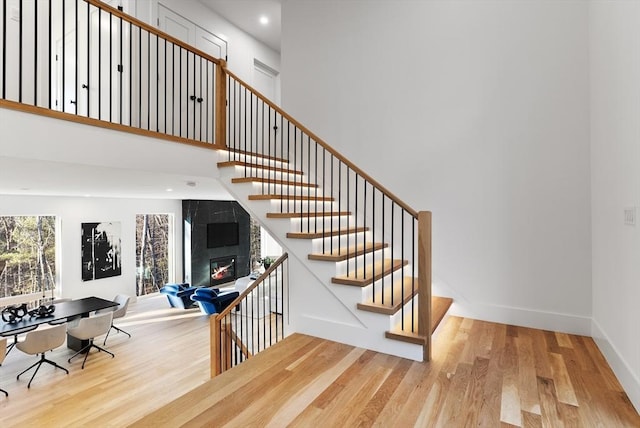 staircase with a large fireplace and wood-type flooring