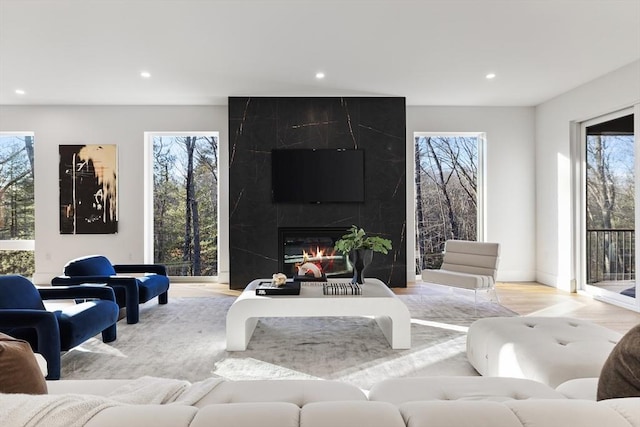 living room featuring a high end fireplace, plenty of natural light, and light hardwood / wood-style flooring