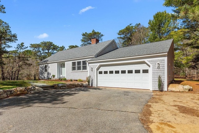 30 Grannys Ln, Orleans, MA 02653 - view of front facade featuring driveway, roof with shingles, a garage, and a chimney