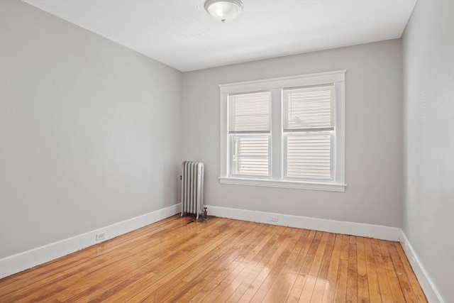 unfurnished room featuring radiator and light wood-type flooring