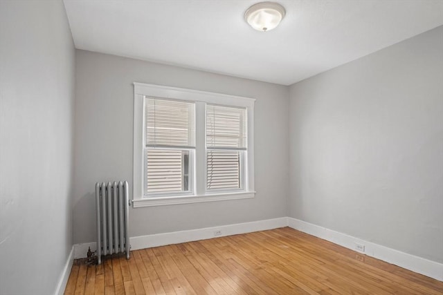 empty room featuring radiator heating unit and hardwood / wood-style floors