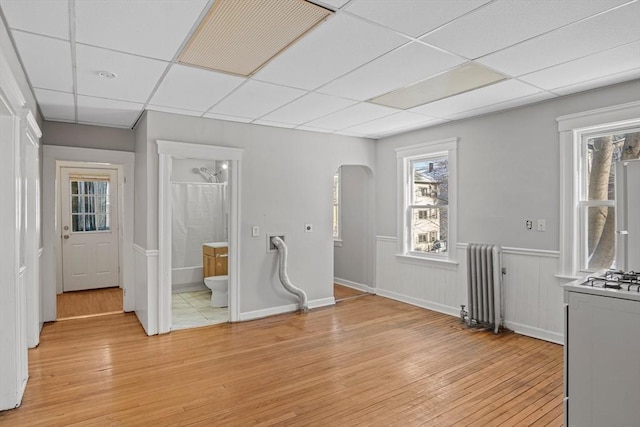 interior space featuring a paneled ceiling, radiator, and light hardwood / wood-style flooring