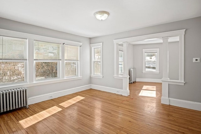 interior space featuring light hardwood / wood-style flooring, radiator heating unit, and ornate columns