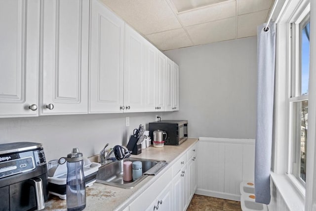 kitchen with a paneled ceiling, sink, and white cabinets