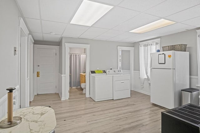 clothes washing area with washing machine and clothes dryer and light hardwood / wood-style floors