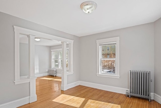 spare room featuring ornate columns, hardwood / wood-style flooring, and radiator