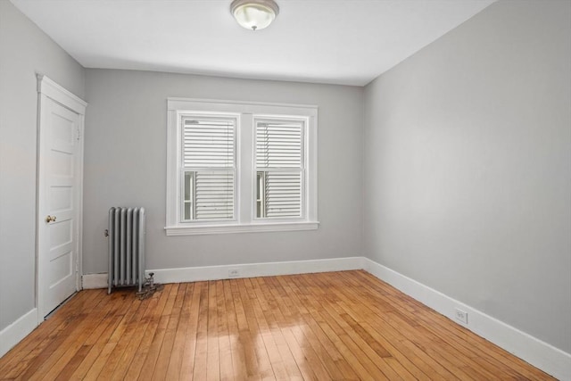 spare room featuring radiator heating unit and light hardwood / wood-style floors