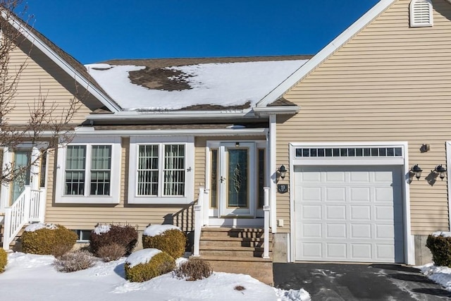 snow covered property entrance with a garage