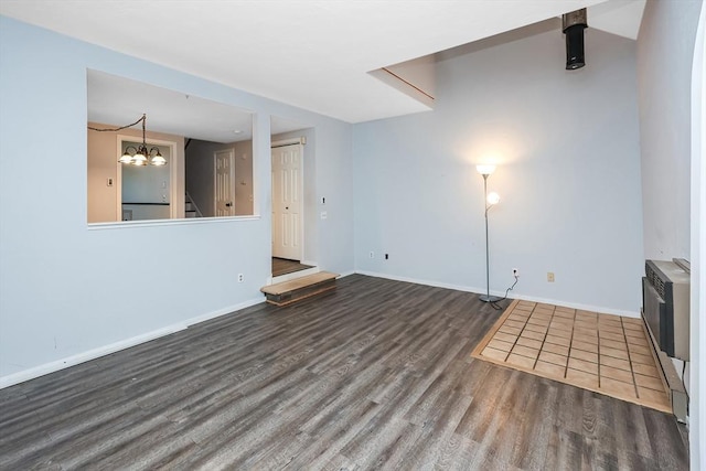 unfurnished living room featuring a wall mounted AC, dark hardwood / wood-style flooring, and a notable chandelier