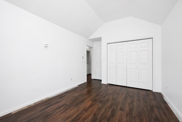 unfurnished bedroom featuring vaulted ceiling, a closet, and dark wood-type flooring