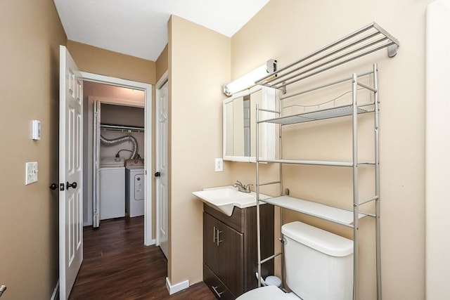 bathroom featuring washer and dryer, vanity, hardwood / wood-style flooring, and toilet