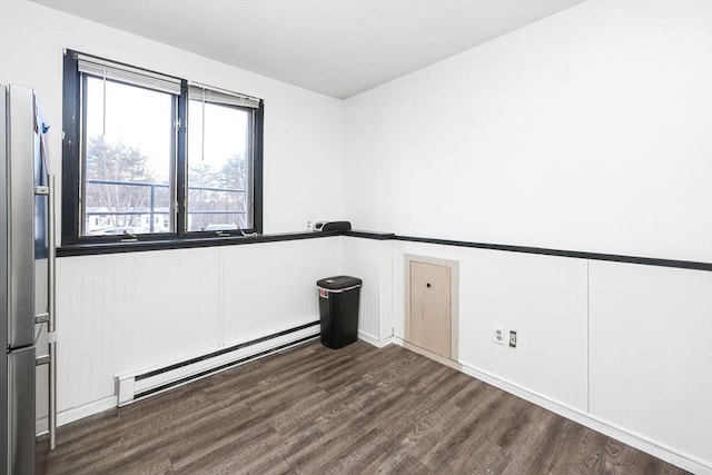 empty room featuring dark wood-type flooring and a baseboard radiator