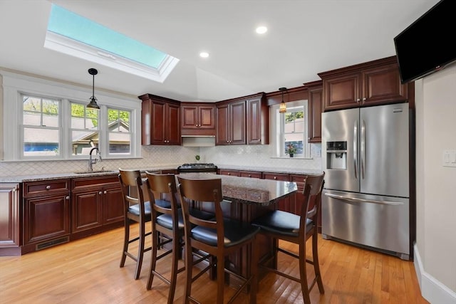 kitchen featuring decorative light fixtures, light wood-style flooring, and stainless steel fridge with ice dispenser