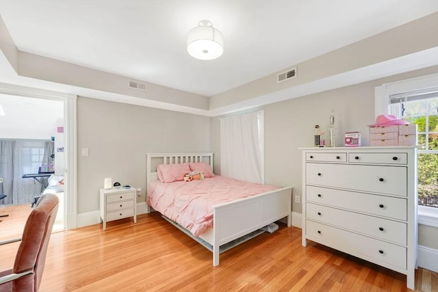 bedroom with visible vents, light wood finished floors, and baseboards