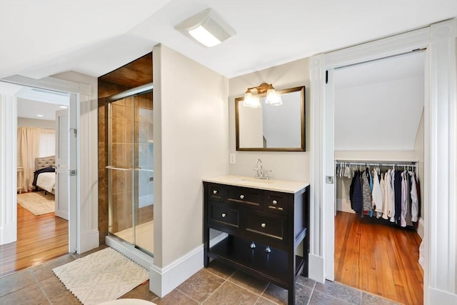 full bath with vanity, baseboards, a stall shower, a walk in closet, and ensuite bath