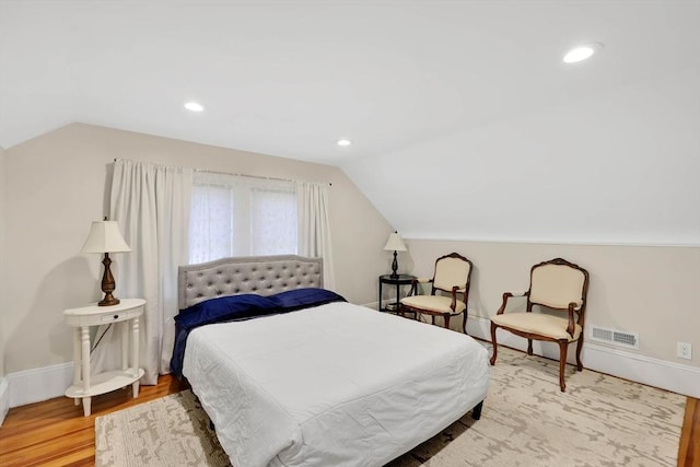 bedroom featuring baseboards, vaulted ceiling, wood finished floors, and visible vents