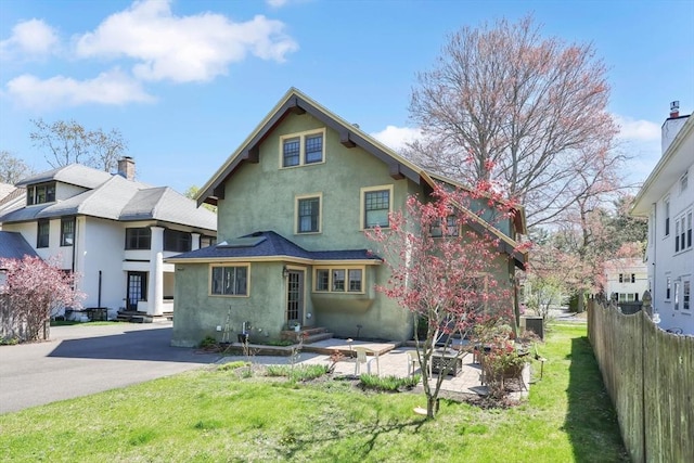 rear view of house with a yard, fence, central air condition unit, and stucco siding