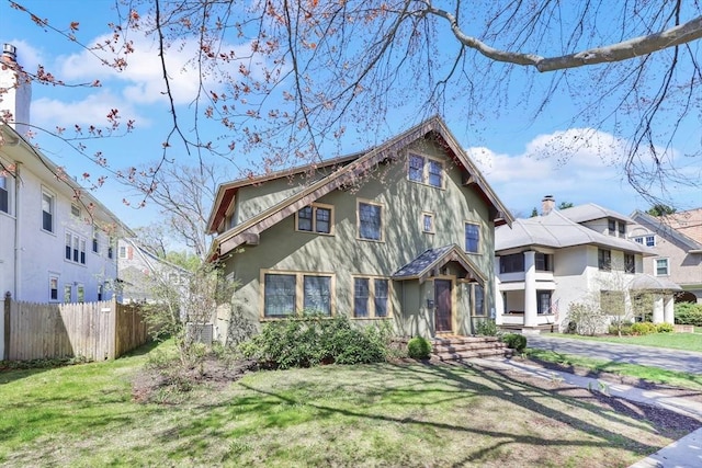 english style home featuring fence, stucco siding, a front yard, and a residential view