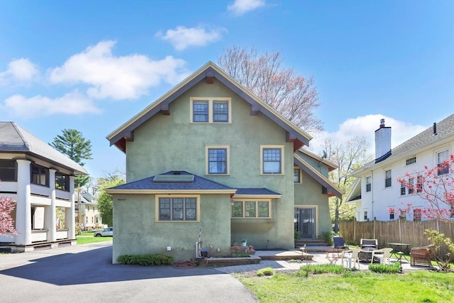 rear view of property with fence, a patio, and stucco siding