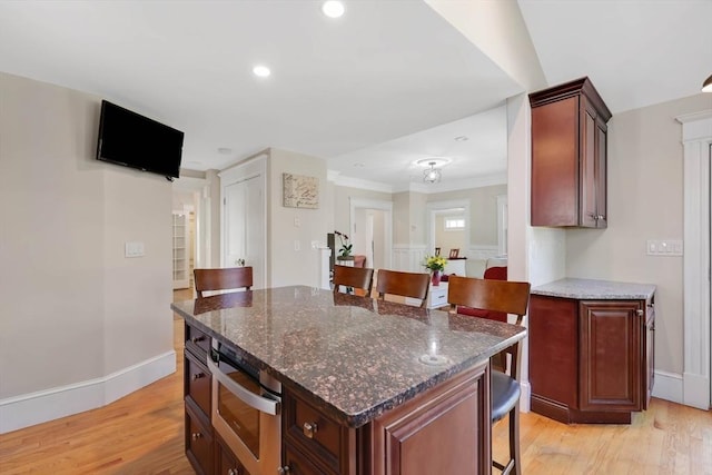 kitchen featuring baseboards, a breakfast bar area, stainless steel oven, recessed lighting, and light wood-style flooring