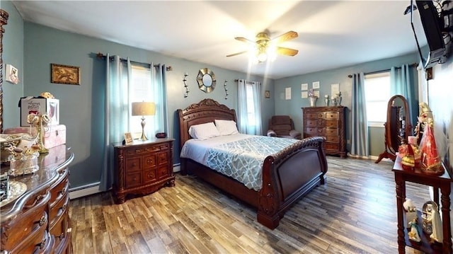 bedroom featuring ceiling fan, a baseboard heating unit, and hardwood / wood-style flooring