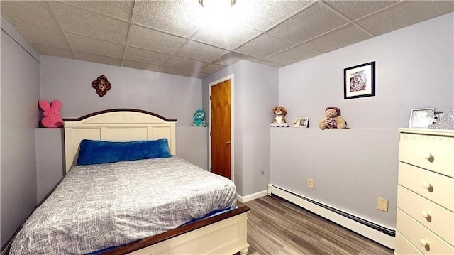 bedroom featuring wood-type flooring, a paneled ceiling, and a baseboard radiator