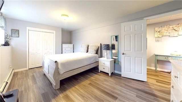 bedroom with hardwood / wood-style floors, baseboard heating, and a closet