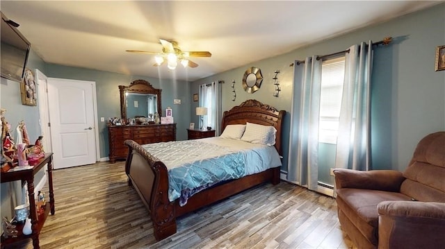 bedroom with hardwood / wood-style floors, ceiling fan, and baseboard heating