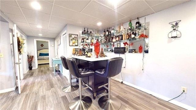 bar featuring a drop ceiling and wood-type flooring