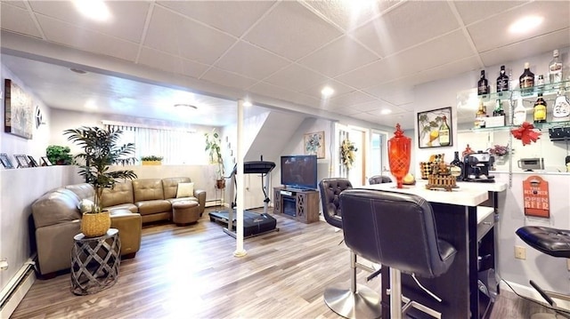 living room featuring a paneled ceiling, hardwood / wood-style floors, and a baseboard radiator