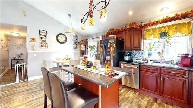 kitchen with a center island, stainless steel appliances, light hardwood / wood-style floors, decorative light fixtures, and vaulted ceiling