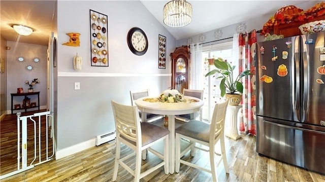 dining space with an inviting chandelier, hardwood / wood-style flooring, vaulted ceiling, and a baseboard radiator