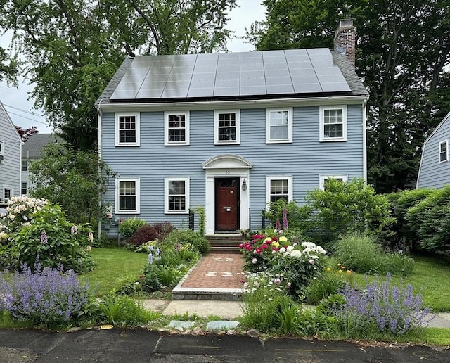 colonial-style house with solar panels and a chimney