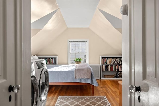 bedroom with washer and clothes dryer, vaulted ceiling, and wood finished floors