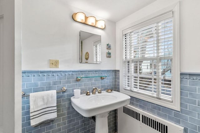 bathroom featuring tile walls, radiator, and wainscoting