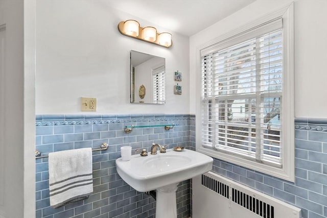 bathroom with a wainscoted wall, tile walls, and radiator heating unit