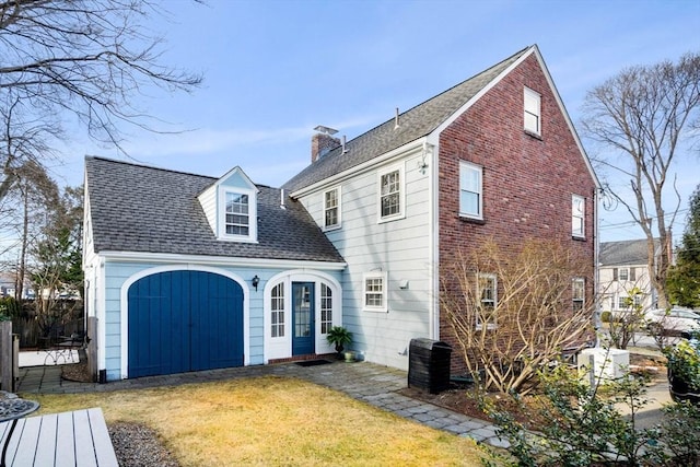 back of house featuring a chimney, a lawn, a shingled roof, and central AC