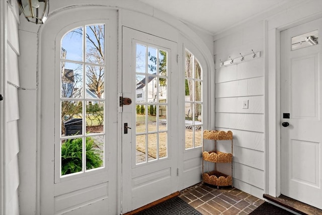 entryway featuring brick floor and crown molding