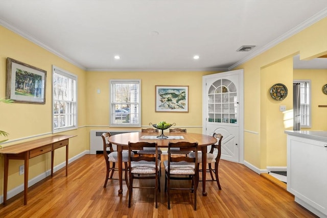 dining area with visible vents, wood finished floors, radiator heating unit, and ornamental molding