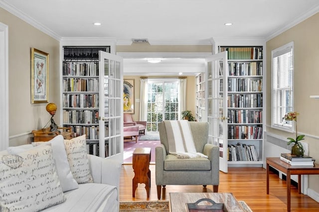 living area with recessed lighting, ornamental molding, french doors, and wood finished floors