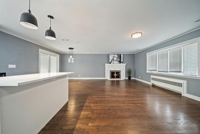 123 Walnut St, Saugus, MA 01906 - unfurnished living room with radiator heating unit, dark wood-style floors, ornamental molding, and a warm lit fireplace
