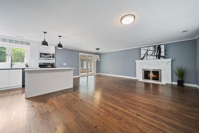 123 Walnut St, Saugus, MA 01906 - kitchen with stainless steel microwave, white cabinetry, dark wood finished floors, a kitchen island, and light countertops