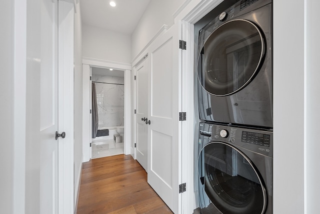 laundry area with stacked washer and dryer, recessed lighting, laundry area, and wood finished floors